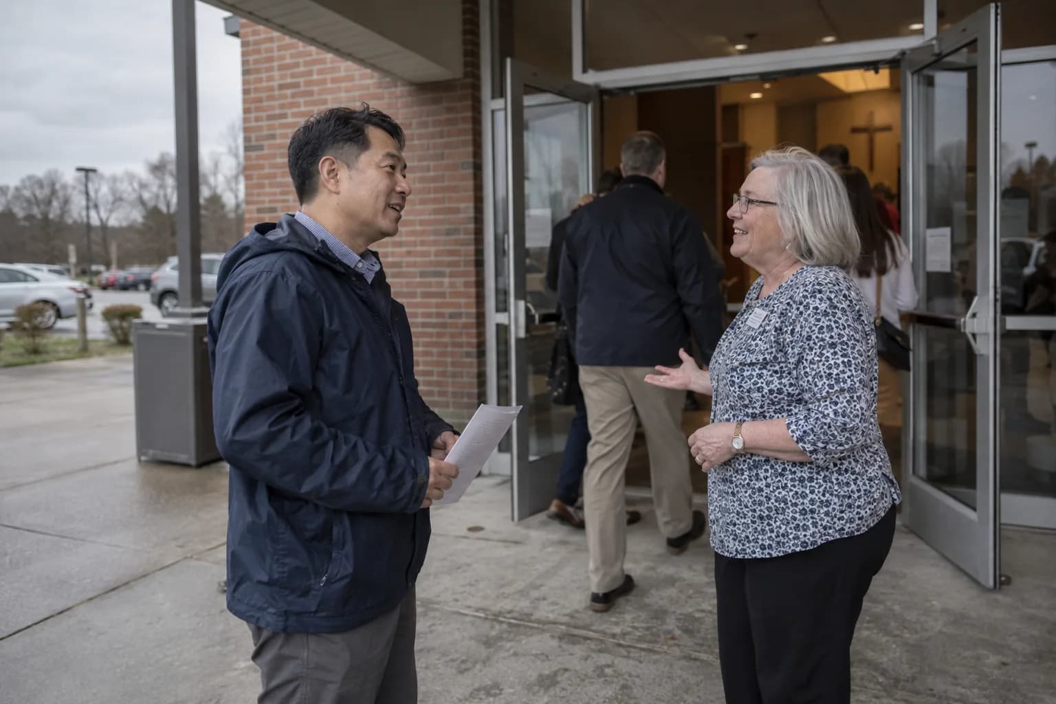 A visitor holding a bulletin is greeted at the glass entrance of a neighborhood church.